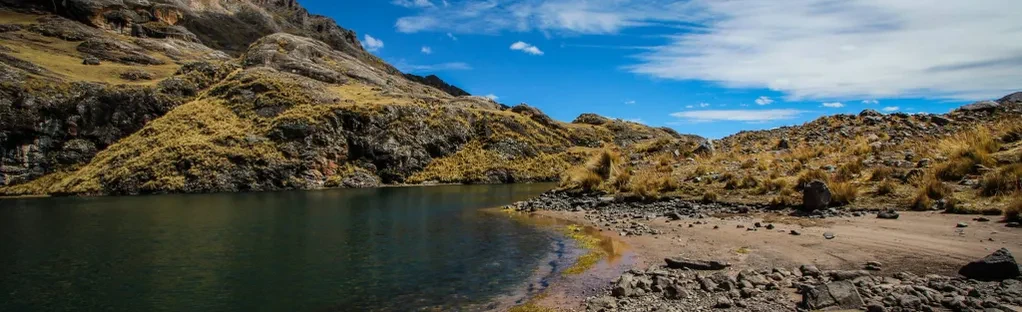 Hikers walking alongside Hatun Pucacocha Lake, one of the largest and most stunning lakes in the 7 Lakes of Ausangate