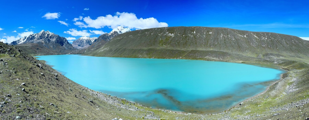 A serene view of Viscachacocha Lake, reflecting the snow-capped peaks of the Nevado Ausangate.