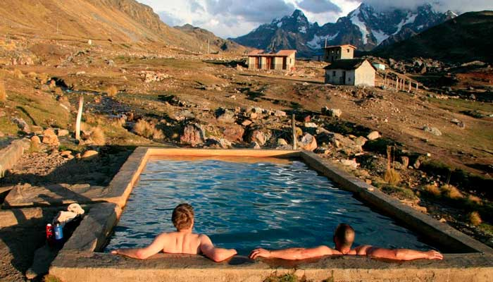 Hikers relaxing in the soothing Ausangate Hot Springs, surrounded by the Andes mountains