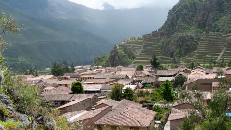 Panoramic view of Ollantaytambo ruins with terraced fields and mountains under a clear blue sky